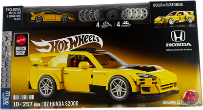 Hot Wheels Brick Shop Mattel official licensed product packaging for the 2007 Honda S2000 building set. The box features a large yellow assembled model car on a black and yellow background, with a clear window at the top showing included metal car and signature rim pieces, and branding for Mattel, Hot Wheels, and Honda.
