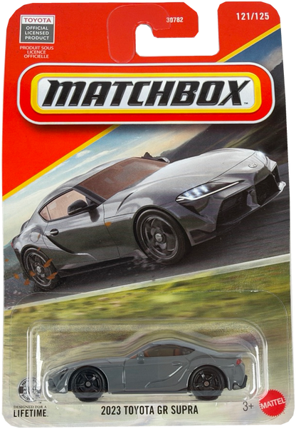 Matchbox diecast toy car of the 2023 Toyota GR Supra, featuring a gray car in a clear blister pack on a orange and yellow Matchbox card.